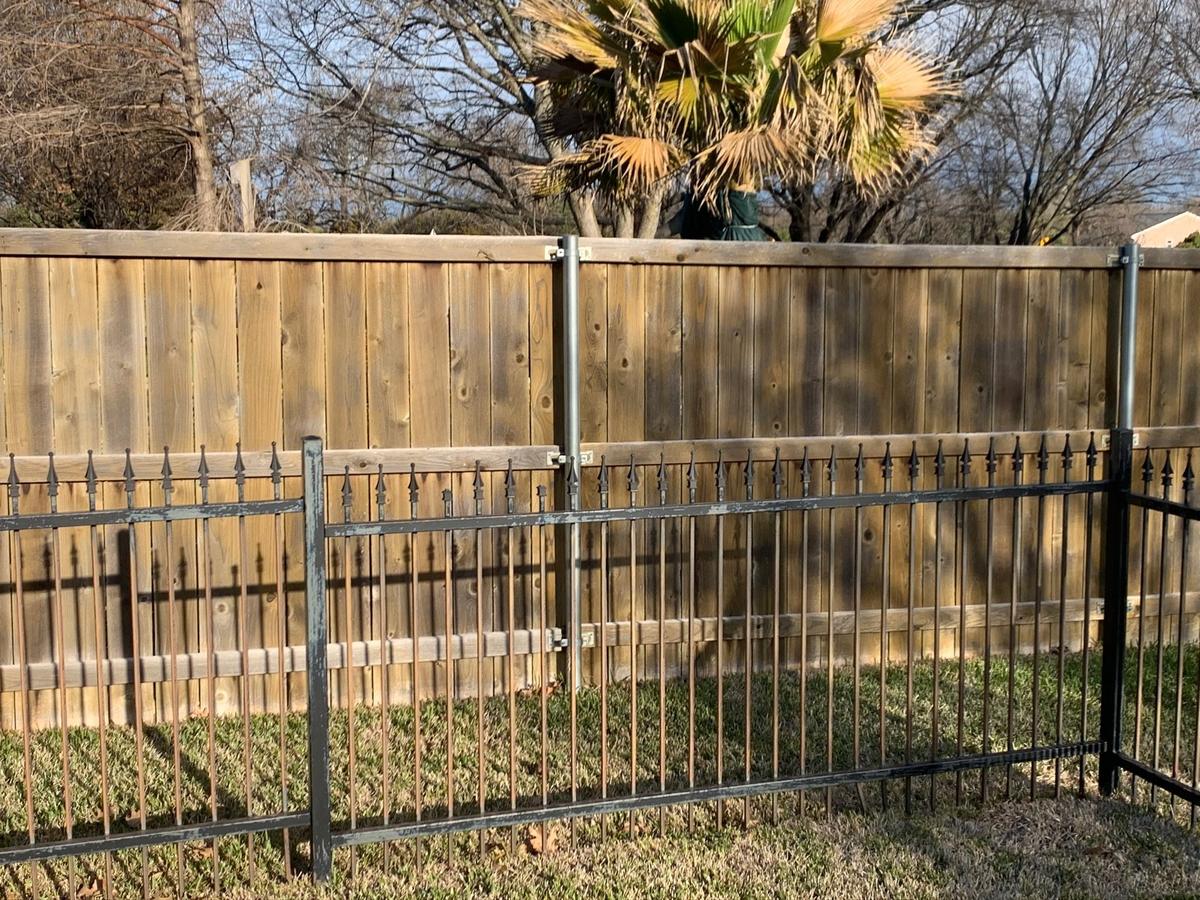 Wrought iron fence with peeling, flaking paint and rust along the rails before restoration