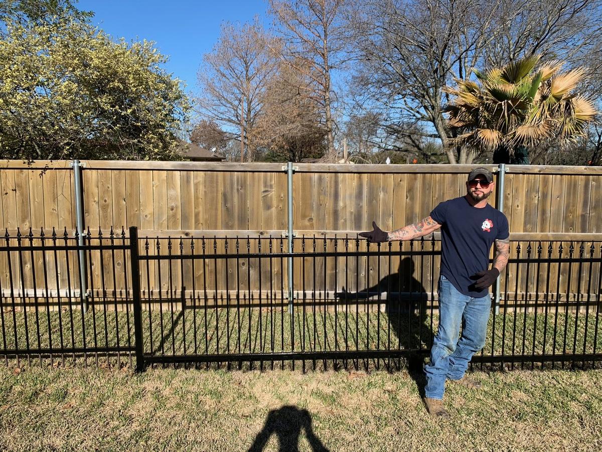 Wrought Iron Rescue owner standing beside a freshly restored glossy black wrought iron fence