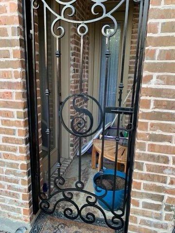 Ornate scrollwork iron gate with S monogram restored to a clean black finish
